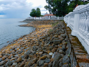 Stone wall by sea against sky
