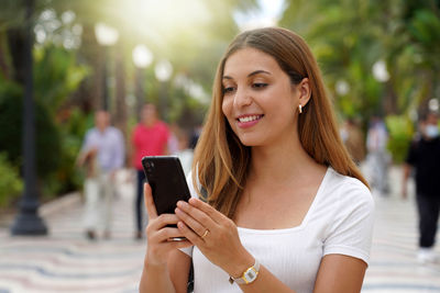 Smiling woman using mobile phone on street