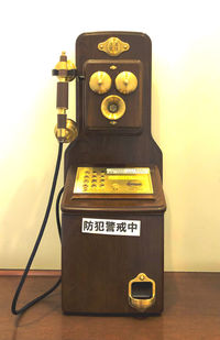 Close-up of telephone booth on table against wall