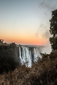 Scenic view of waterfall against sky during sunset