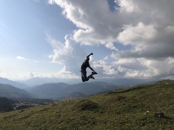 Man jumping on mountain against sky