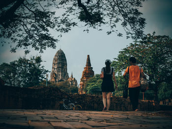 Rear view of people walking on temple against sky