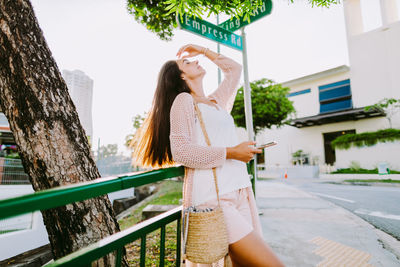 Woman with hand in hair standing by railing