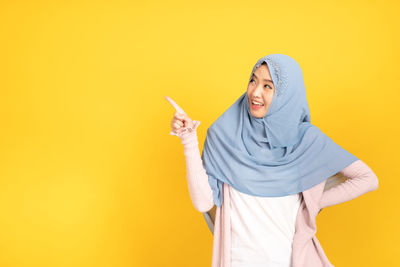 Mid adult woman standing against yellow background