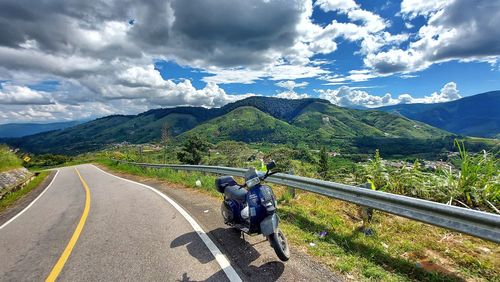 Man riding motorcycle on road against sky