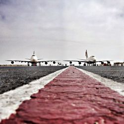 Surface level of airport runway and airplanes against cloudy sky