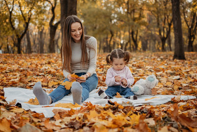 Happy woman with autumn leaves against trees