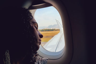 Young woman resting head on airplane window