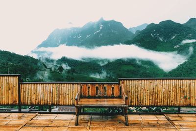 Empty bench on building terrace against mountains