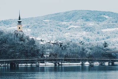 Bridge over river in city against sky during winter