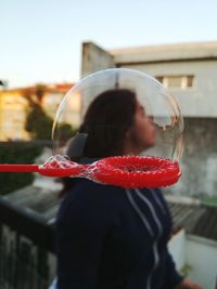 Close-up of woman seen through bubble on red wand