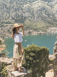 Woman standing by tree against mountain