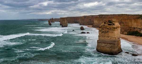 View of rocks in sea against cloudy sky