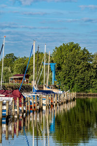 Sailboats moored in lake against sky