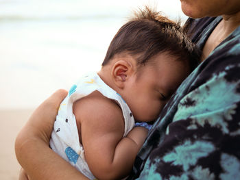 Mom carry sleeping baby at the beach