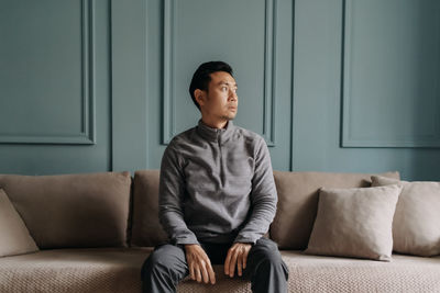 Young man sitting on sofa at home