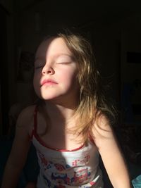 Close-up of cute girl with eyes closed sitting at home