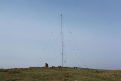 Low angle view of antenna in a green field and blue sky background