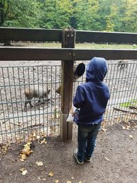 Rear view of man standing by fence