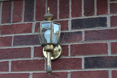 Close-up of electric lamp on brick wall