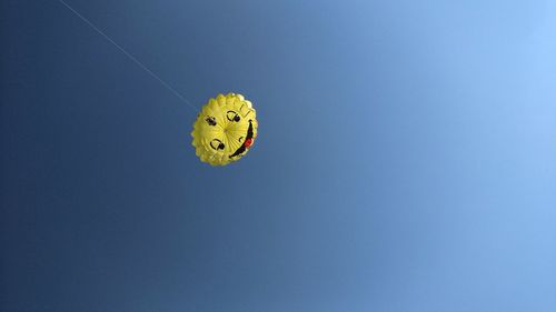 Low angle view of yellow parachute against clear blue sky