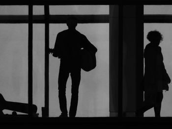 Silhouette of man standing by window