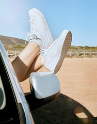 Low section of woman sitting on car