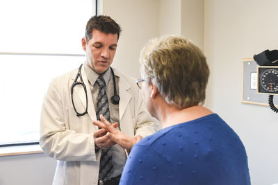 Doctor examining the hand of an older patient in a clinical setting.