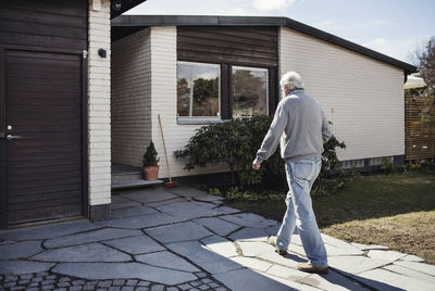 Full length of senior man walking towards house on sunny day