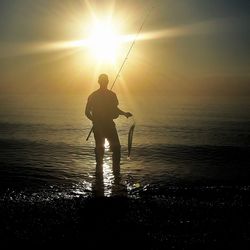 Silhouette of man fishing in sea