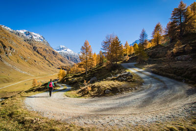 Rear view of woman walking on mountain road