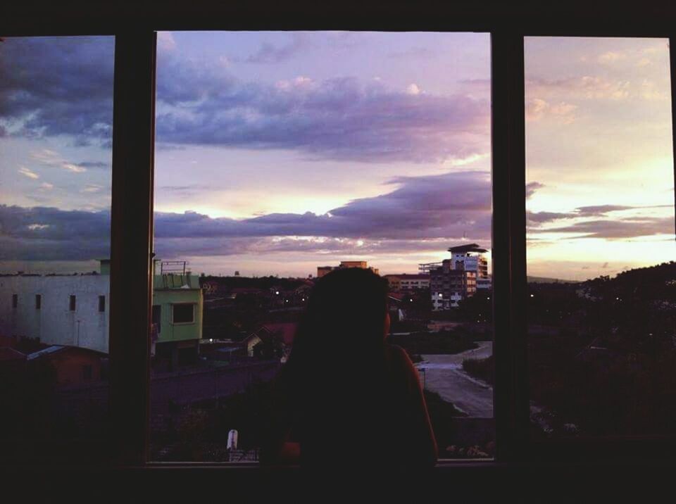 sky, window, silhouette, cloud - sky, sunset, indoors, lifestyles, person, glass - material, cloud, built structure, architecture, rear view, leisure activity, looking through window, transparent, men, sitting