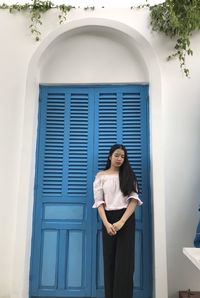 Woman standing by window of building