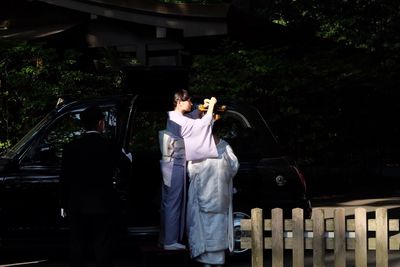 Rear view of man and woman standing against trees