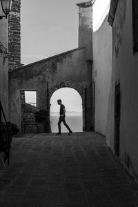 Full length of woman walking on footpath amidst buildings in city