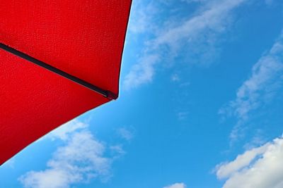 Low angle view of red parasol against blue sky