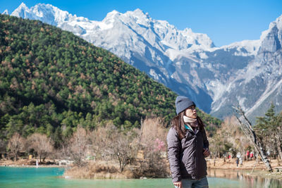 Woman wearing backpack while standing against mountains during winter