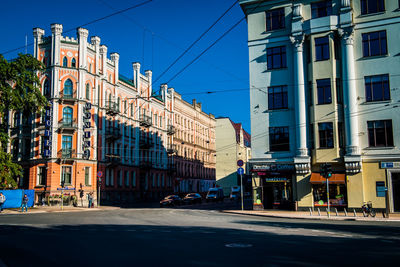 Road by buildings against sky in city