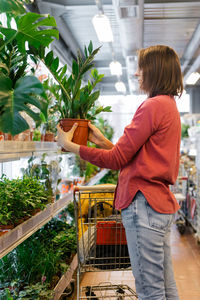 Midsection of woman standing by store buying plants