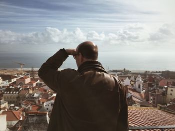 Man looking at cityscape against sky