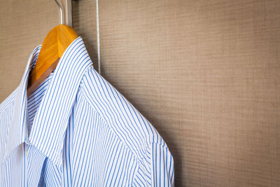 Close-up of blue shirt hanging on brown wall