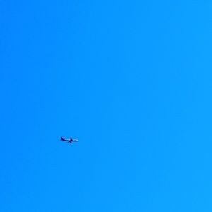 Low angle view of airplane against clear blue sky