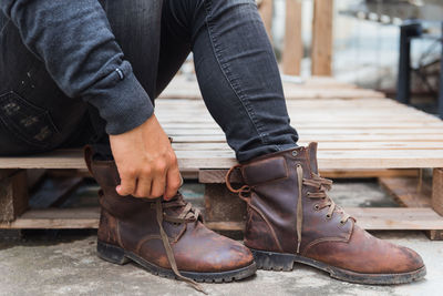 Low section of man tying shoelace while sitting on palette