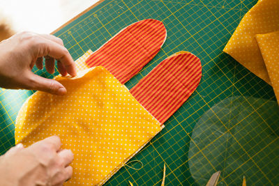 Cropped hands making fabric artwork on cutting mat