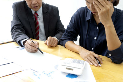 Midsection of man and woman wearing mask on table