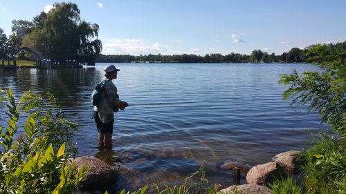 Side view of man standing in lake against sky