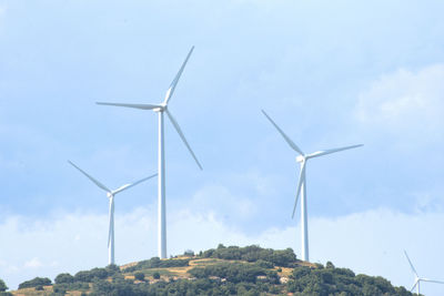 Low angle view of windmill on hill against sky