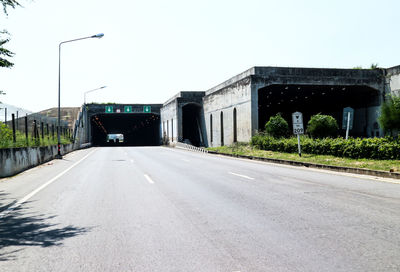 Road leading towards city against clear sky