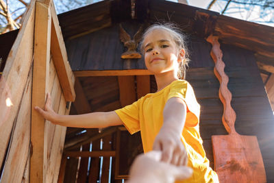 Girl plays in creative handmade treehouse in backyard, summer activity, happy childhood, cottagecore