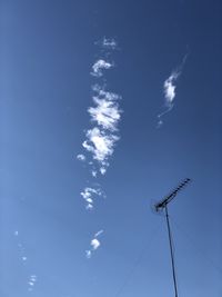 Low angle view of vapor trail against blue sky on sunny day